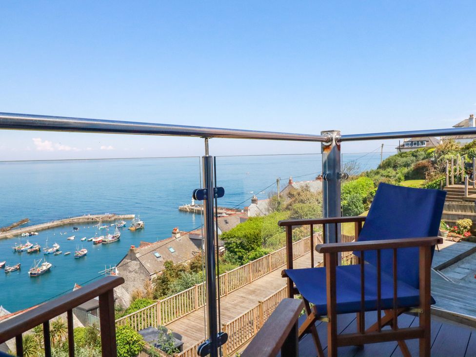 A balcony with a chair overlooking boats at Trewollock in Mevagissey