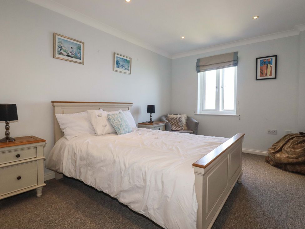 A bedroom with a bed beside a window at Trewollock in Mevagissey