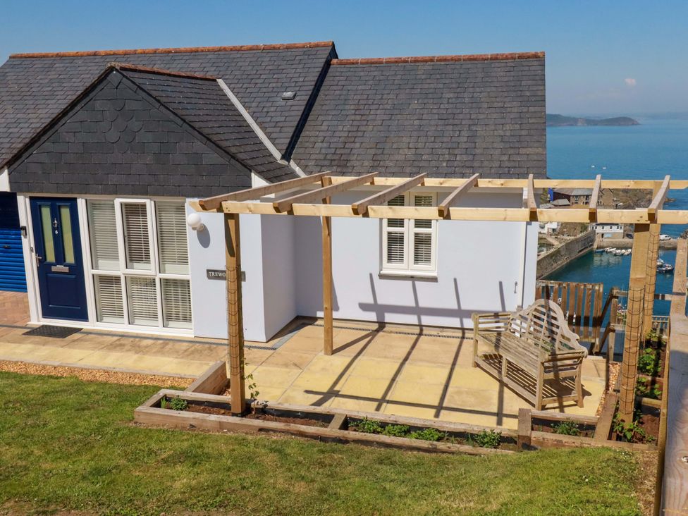 A house with a pergola and bench overlooking water at Trewollock in Mevagissey
