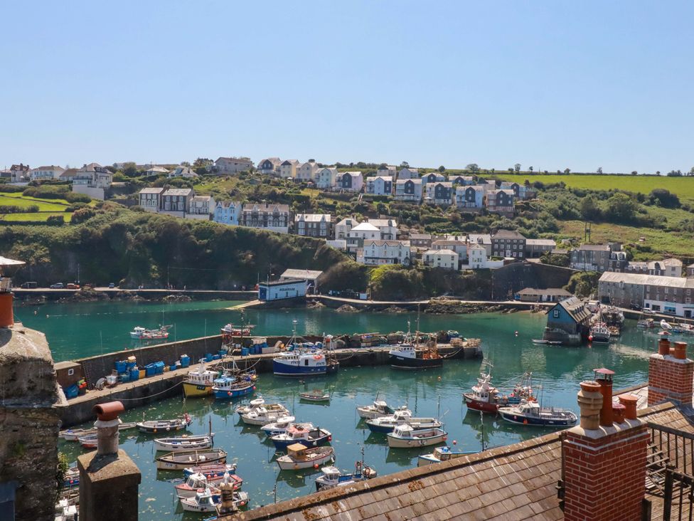A view of a harbor with boats and buildings in the background at Trewollock, Mevagissey
