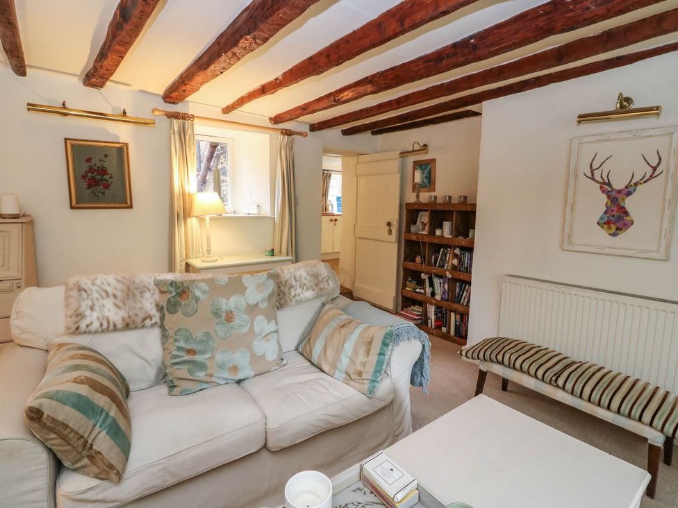 A living room with a sofa and bookshelf at Sciora Cottage