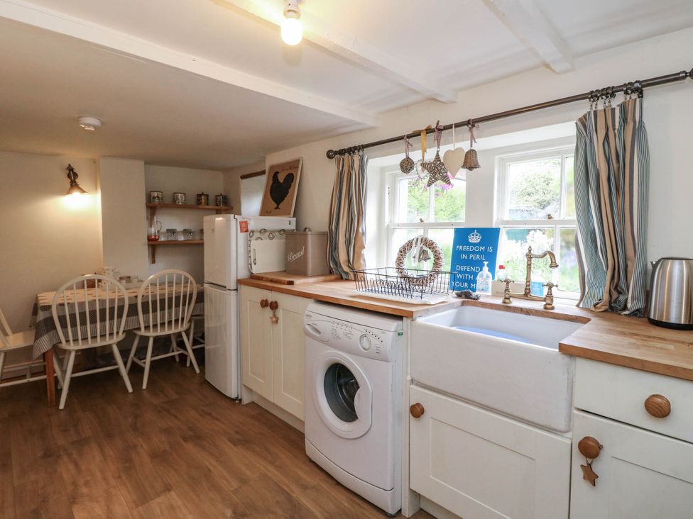 A kitchen with a sink and a washing machine at Sciora Cottage