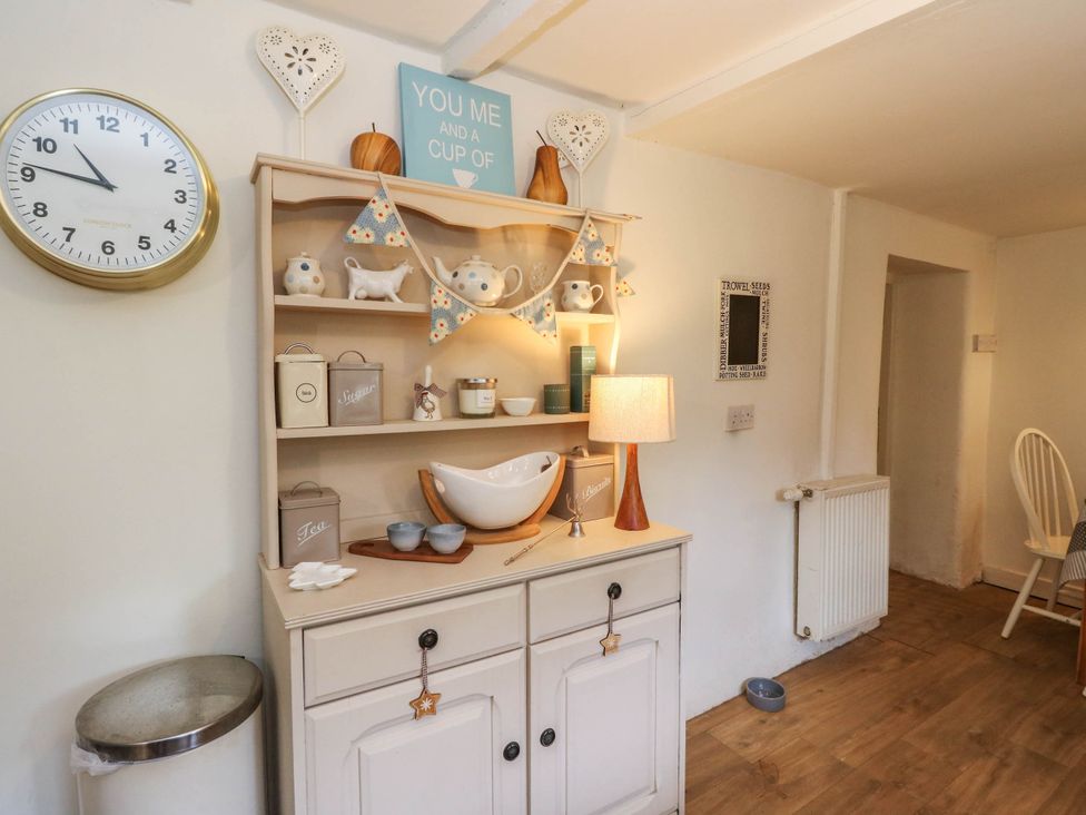 A kitchen with a shelf displaying decorative items and a clock at Sciora Cottage