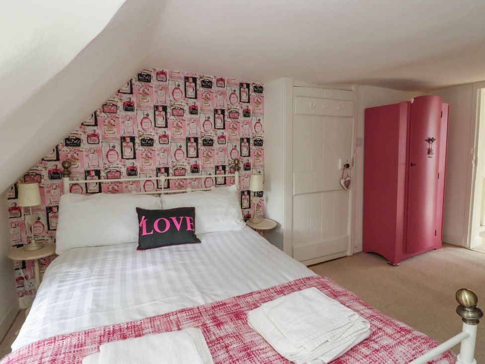 A bedroom with a bed and pink wardrobe at Sciora Cottage