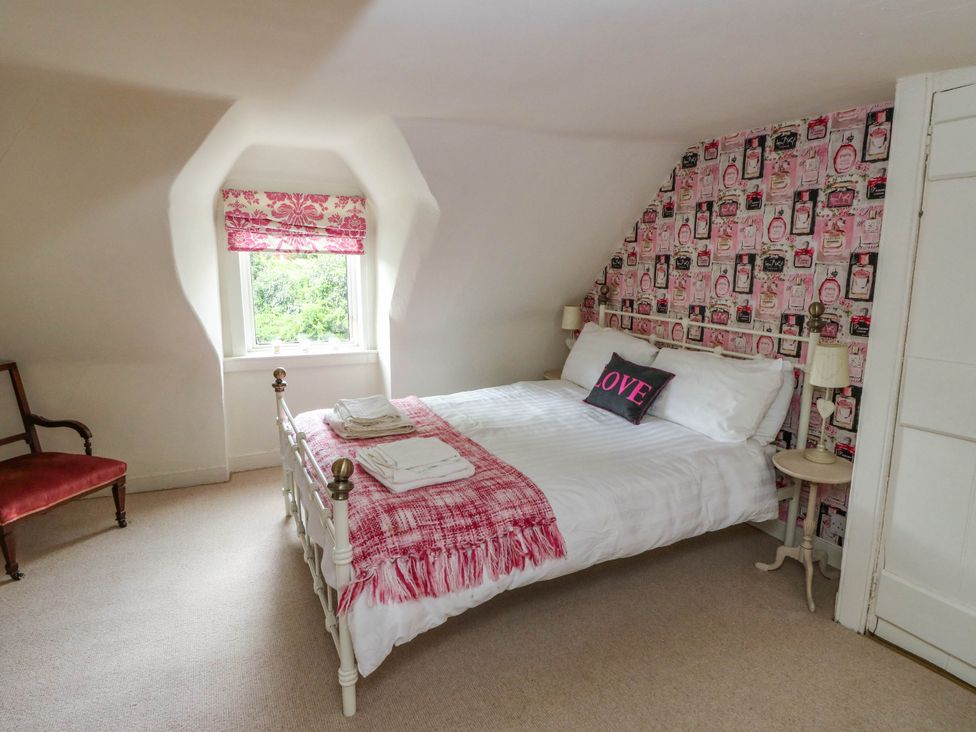 A bedroom with a bed and chair at Sciora Cottage
