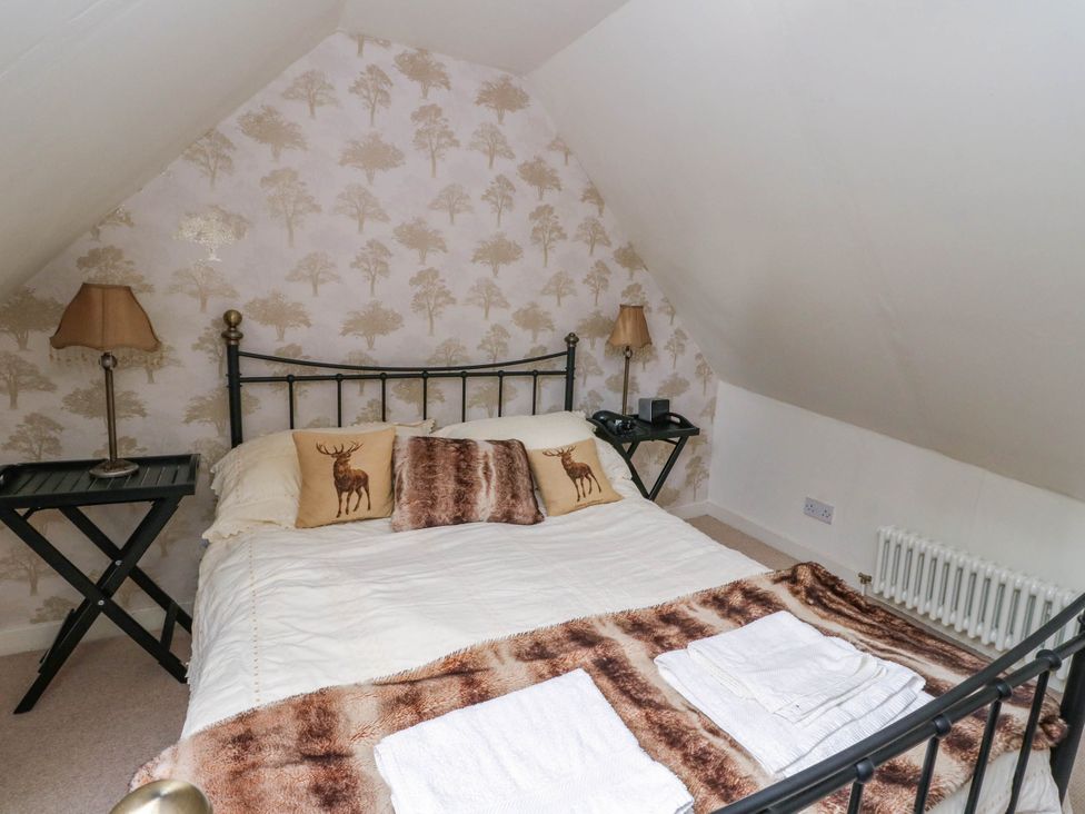 A bedroom with a bed, bedside table, and lamp at Sciora Cottage