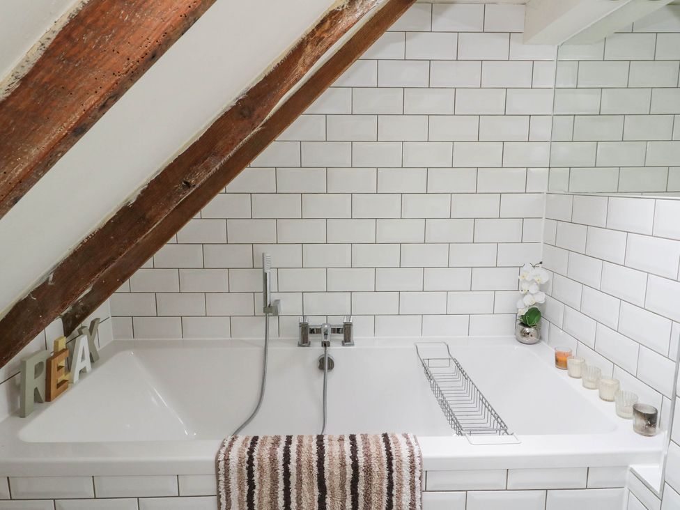 A bathtub with a towel and a decorative plant at Sciora Cottage