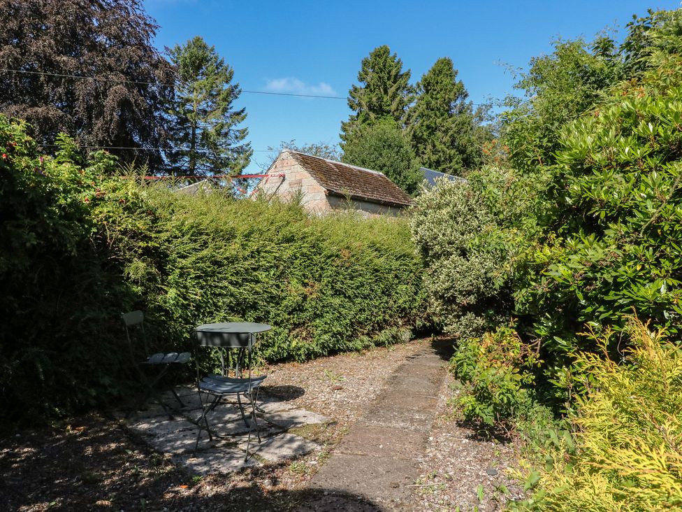 A garden with a table and chair at Sciora Cottage in Crieff