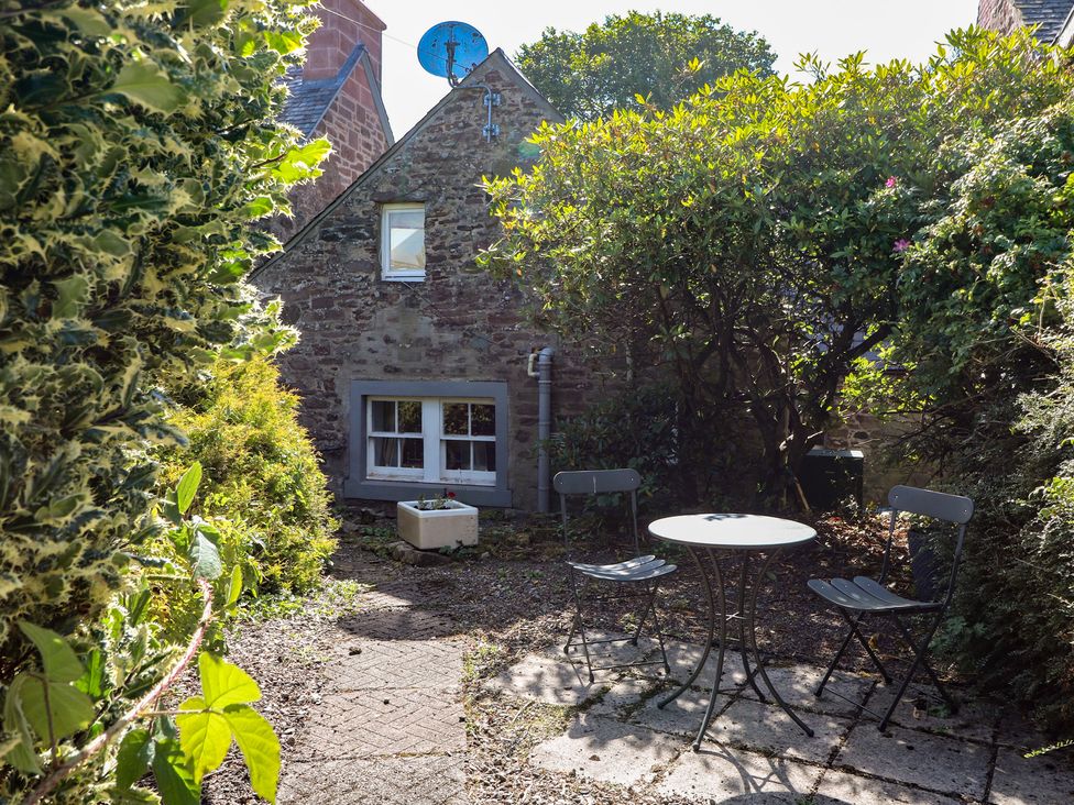 A garden with a table and chairs at Sciora Cottage in Crieff