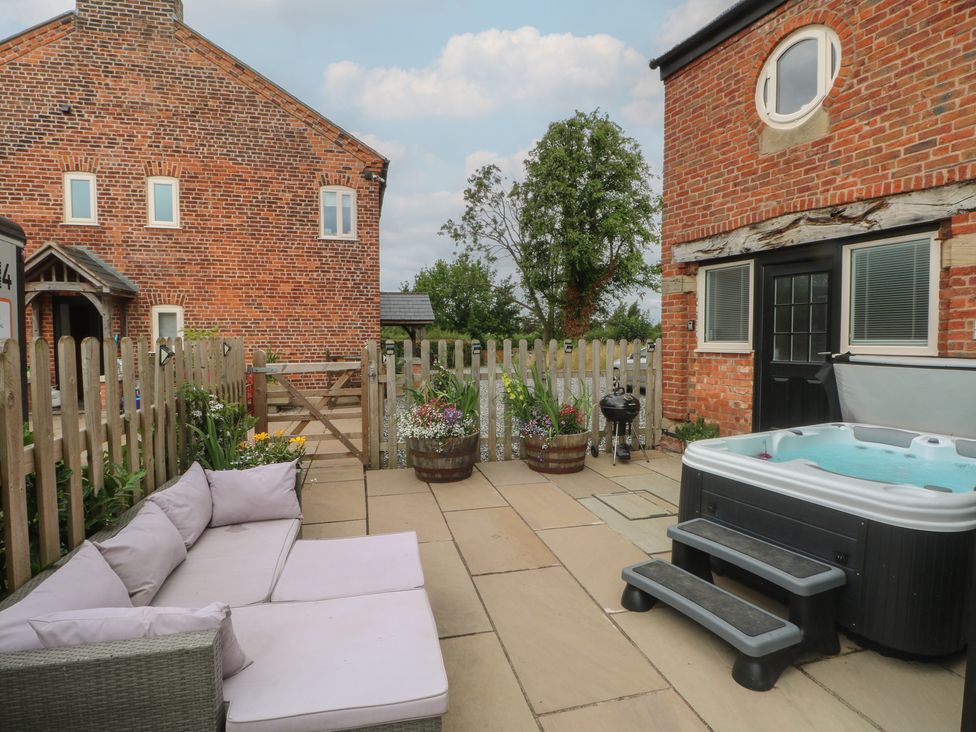 An outdoor space with a hot tub and sofa at Barn 1 in Day Green near Rode Heath