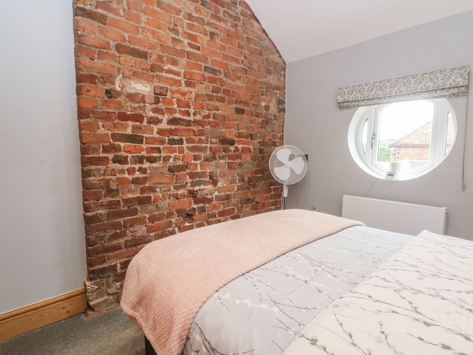 A bedroom with a brick wall and bed at Barn 1 Day Green near Rode Heath