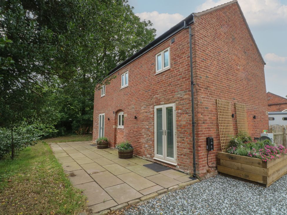 A brick house with a patio and plants at Barn 1 in Day Green near Rode Heath