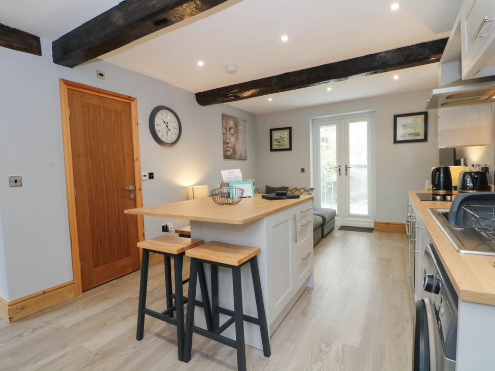 A kitchen with bar stools and a clock at Barn 2 Day Green near Rode Heath