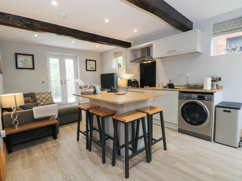 A kitchen with a washing machine and bar stools at Barn 2 Day Green near Rode Heath