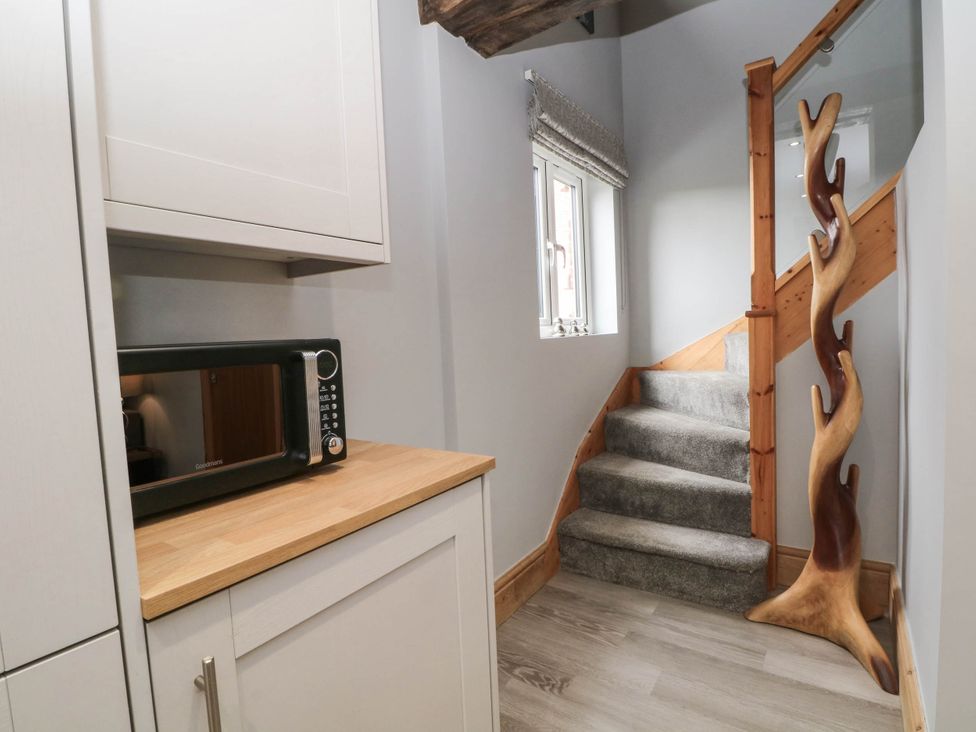 A hallway with a microwave and wooden stairs at Barn 2 Day Green near Rode Heath