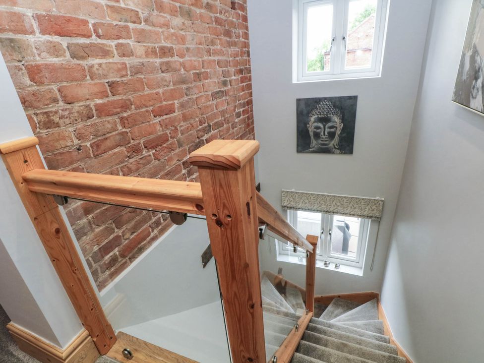 A staircase with wooden railing and brick wall at Barn 2 Day Green near Rode Heath