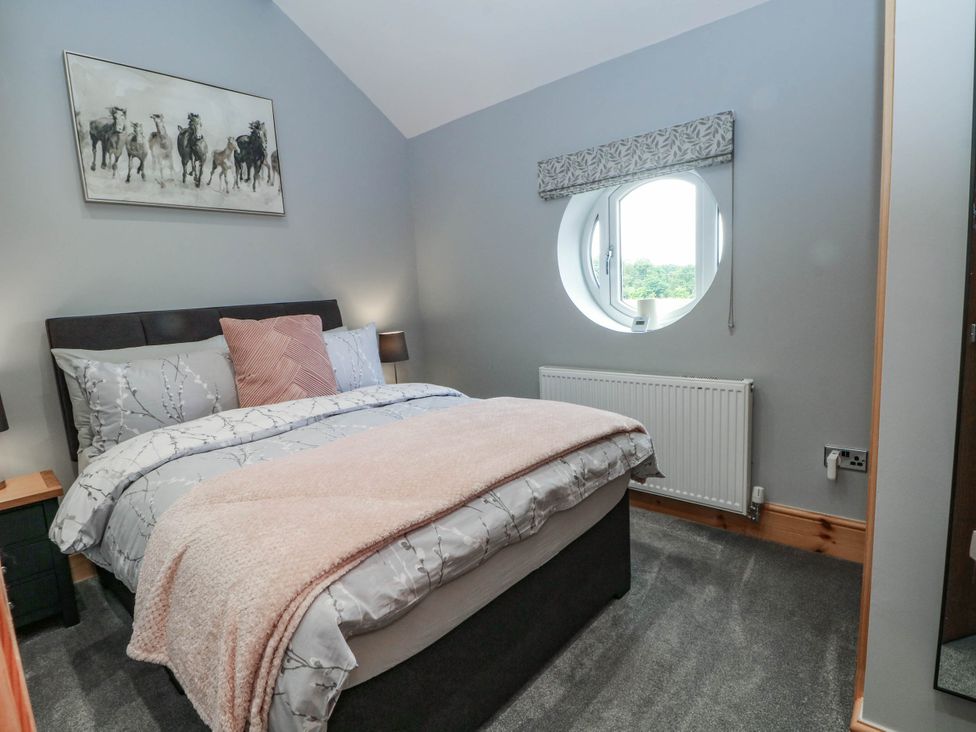 A bedroom with a bed and a round window at Barn 2 in Day Green near Rode Heath