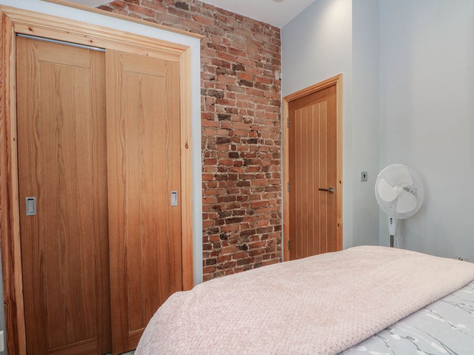 A bedroom with sliding doors and a brick wall at Barn 2 Day Green near Rode Heath