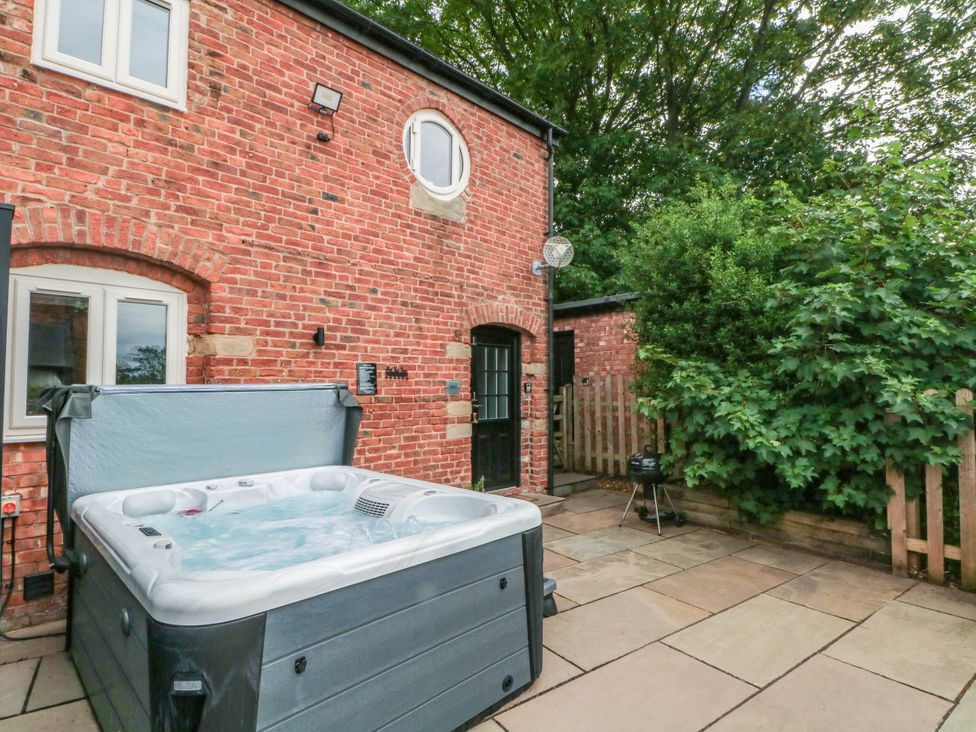An outdoor area with a hot tub and patio at Barn 2 Day Green near Rode Heath
