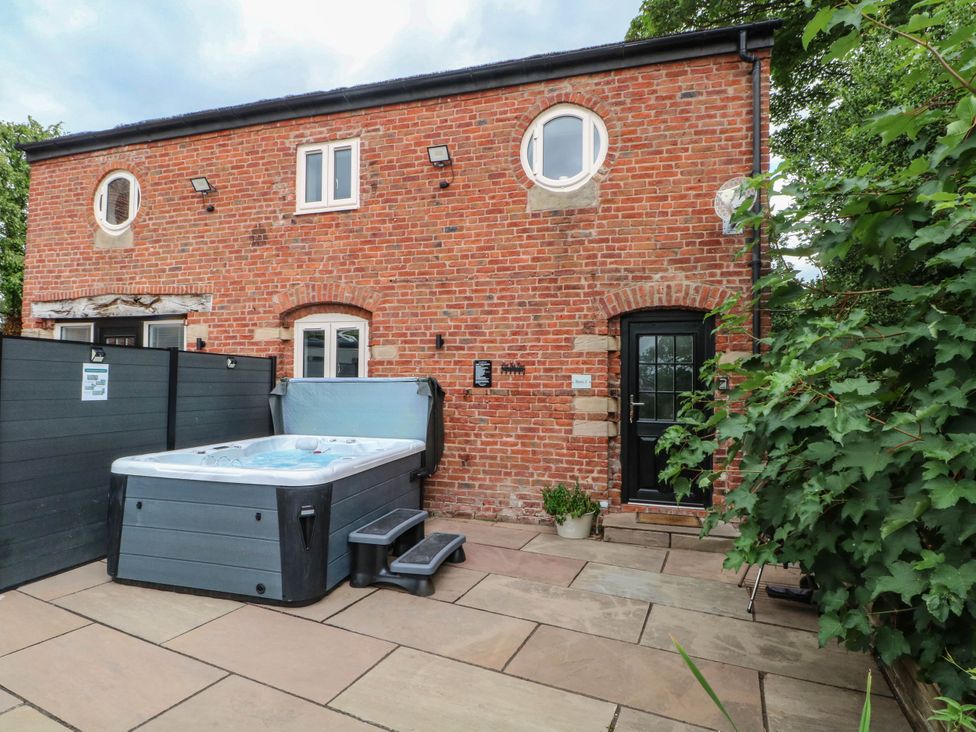 An outdoor area with a hot tub and brick wall at Barn 2 Day Green near Rode Heath