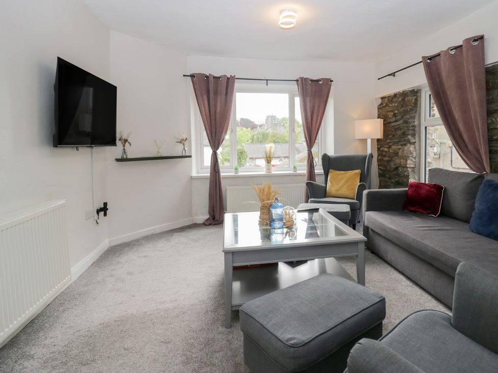 A living room with a sofa and television at Courtyard Cottage