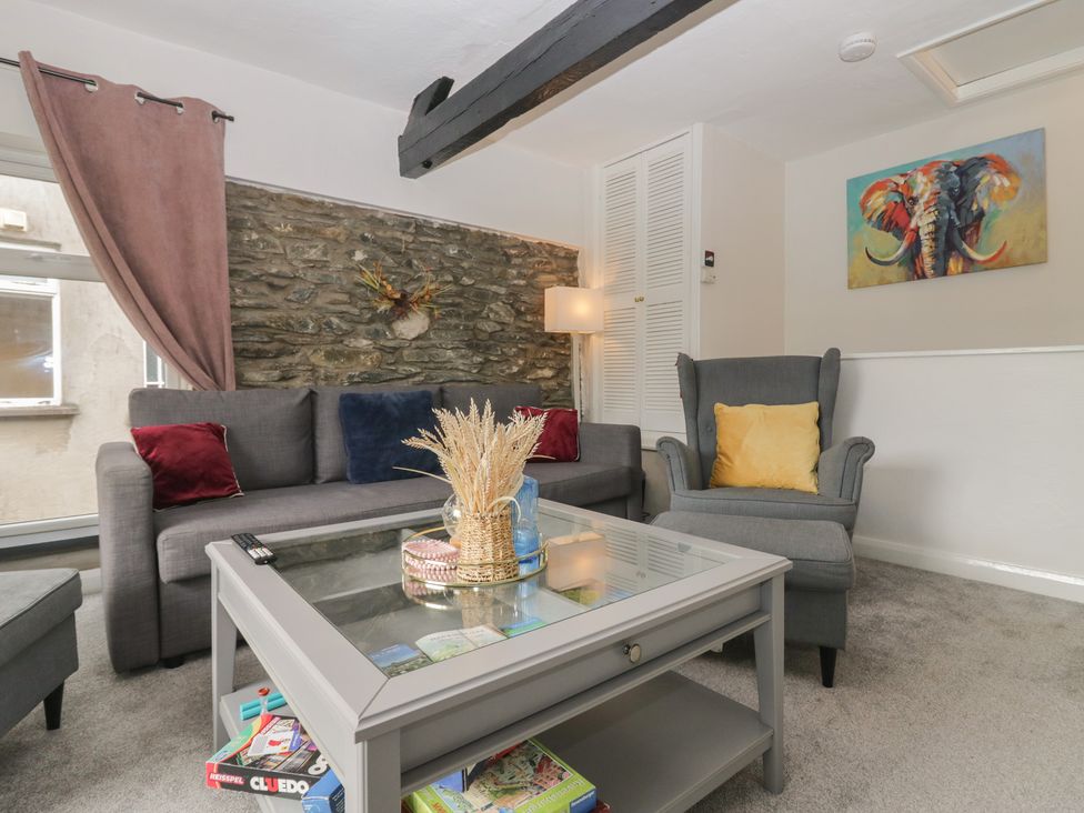 A living room with a sofa, armchair, and table at Courtyard Cottage 