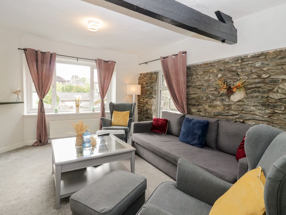 A living room with a sofa and armchair at Courtyard Cottage
