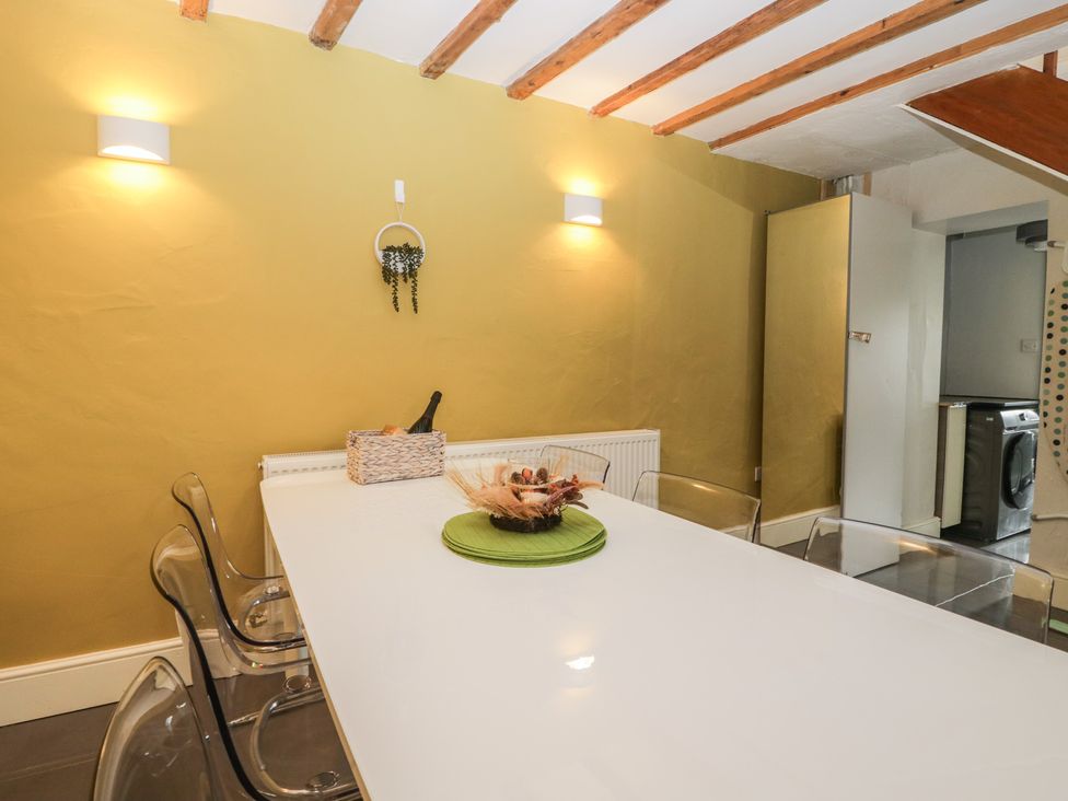 A dining room with a white table and chairs at Courtyard Cottage