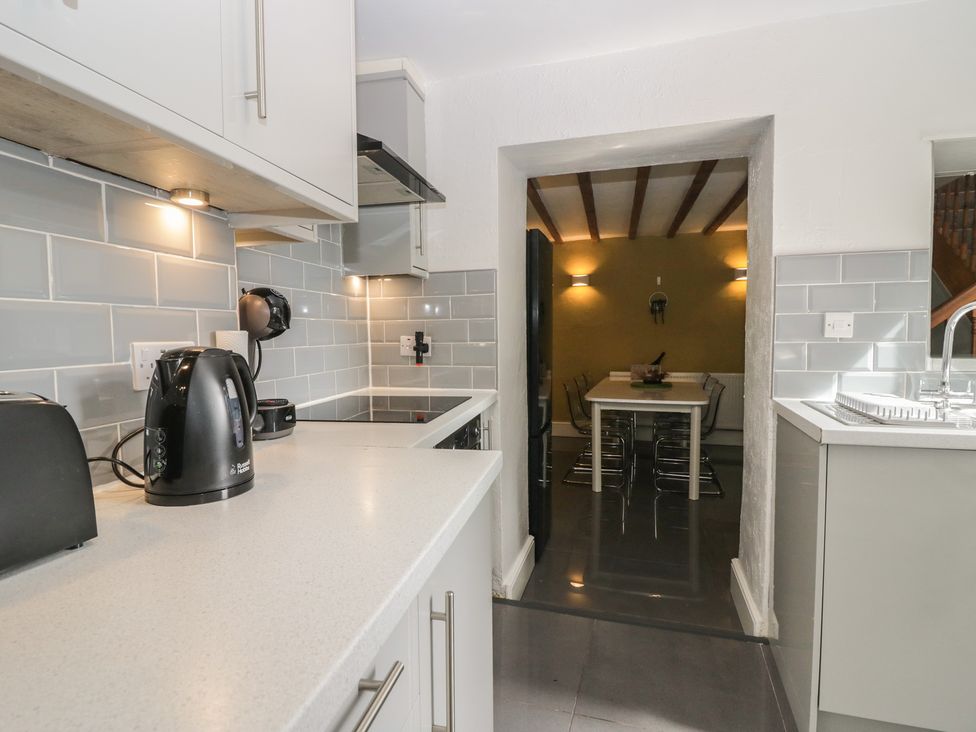 A kitchen with appliances and a view into the dining area at Courtyard Cottage