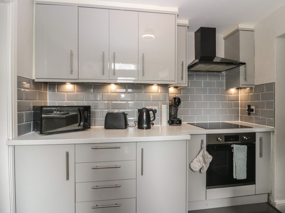 A kitchen with appliances and cabinets at Courtyard Cottage