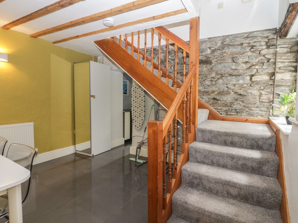 A hallway with stairs and kitchen appliances at Courtyard Cottage