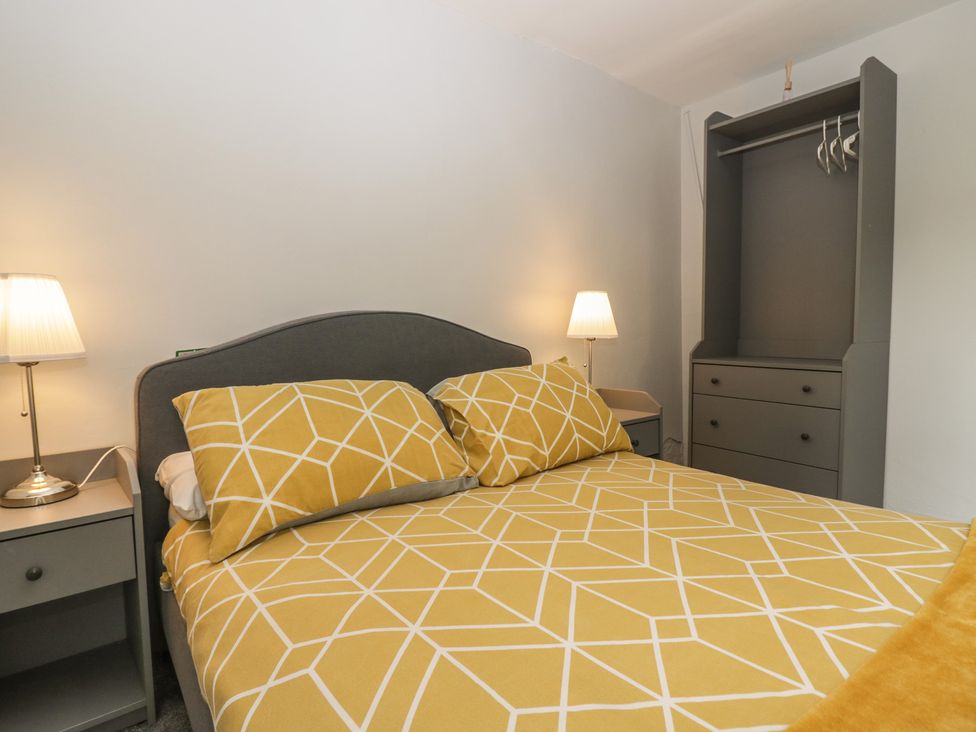 A bedroom with a bed, bedside table, lamp and wardrobe at Courtyard Cottage