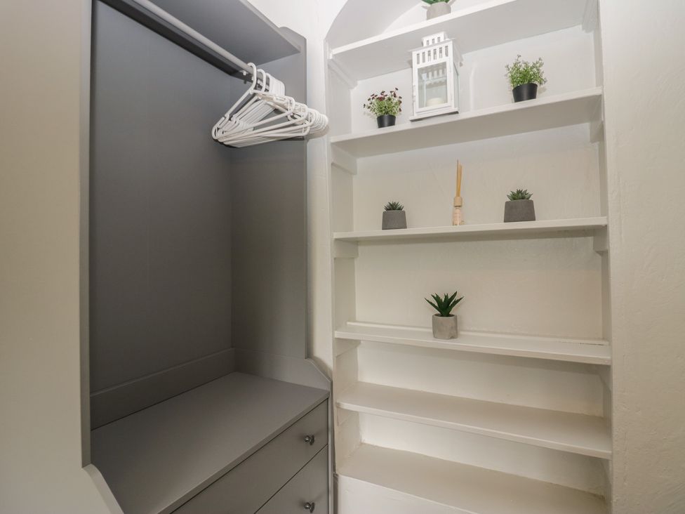 A closet with shelves and storage drawers at Courtyard Cottage
