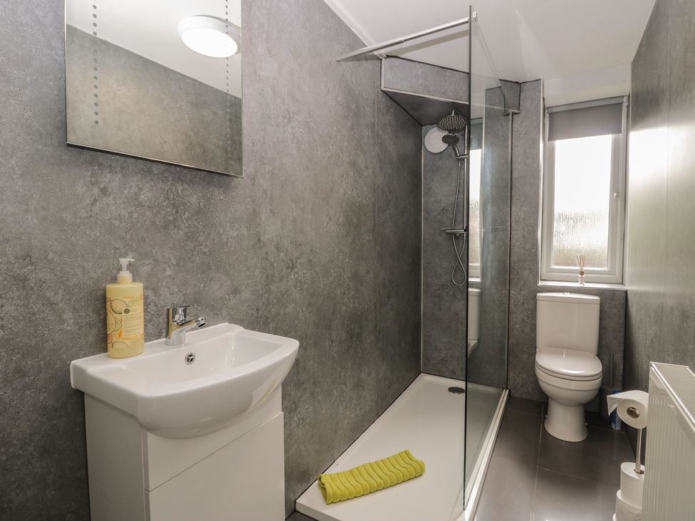 A bathroom with a sink, toilet, shower, and mirror at Courtyard Cottage