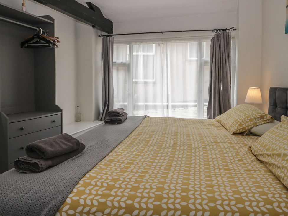 A bedroom with a bed and shelves at Courtyard Cottage