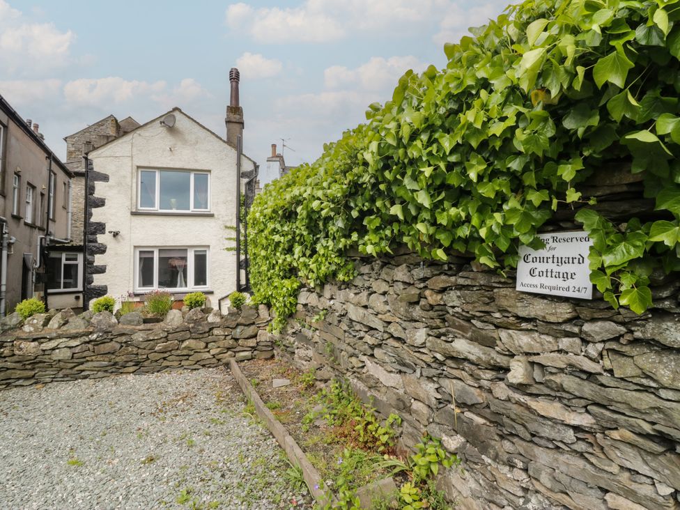 Exterior view of Courtyard Cottage with a stone wall and ivy in 