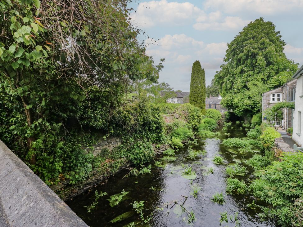 A stream surrounded by trees and plants at Courtyard Cottage
