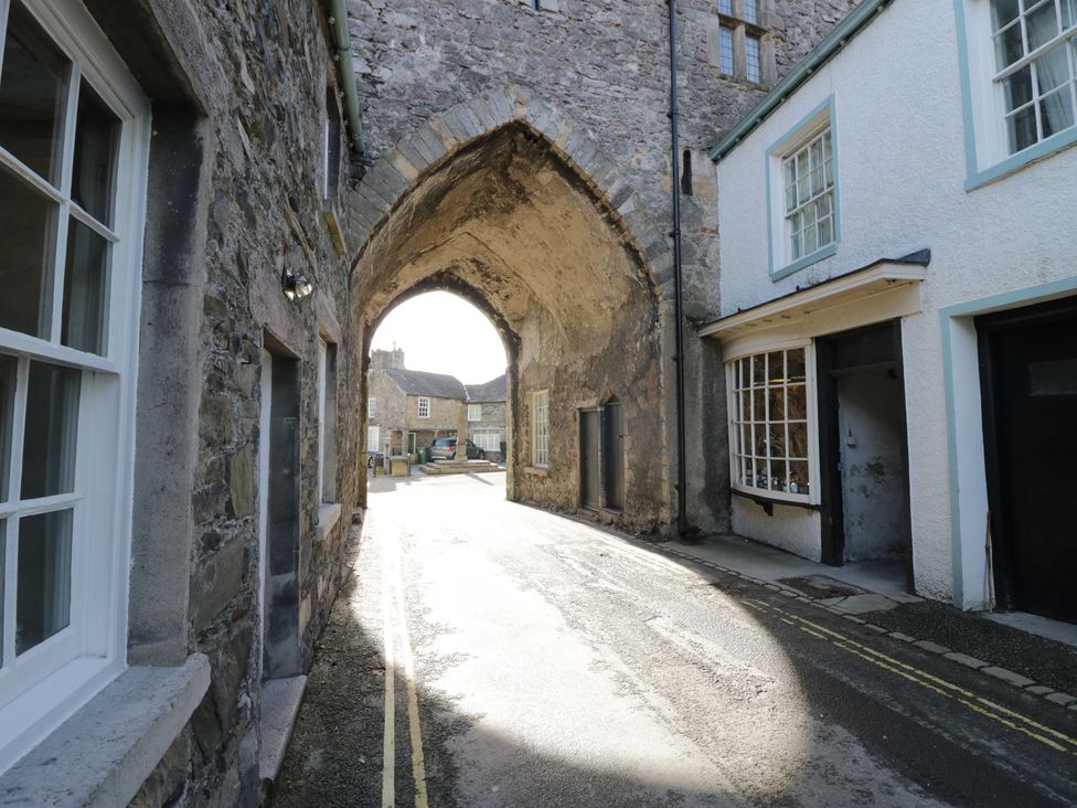 An arched doorway with stone walls and buildings on either side at Courtyard Cottage