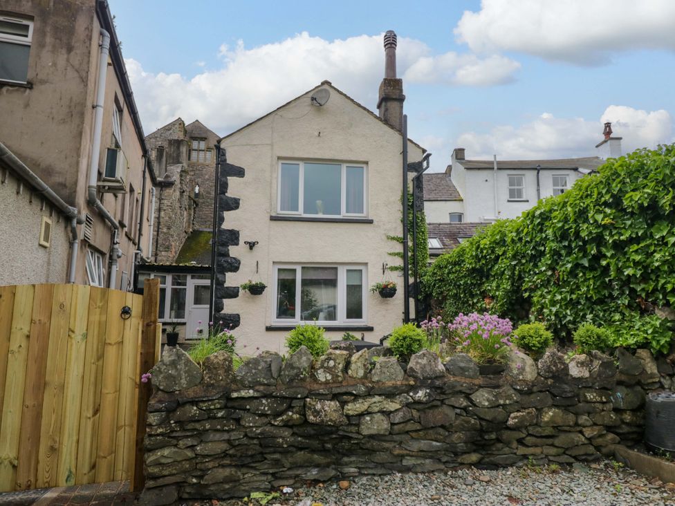 A house with a stone wall and garden at Courtyard Cottage in Cartmel