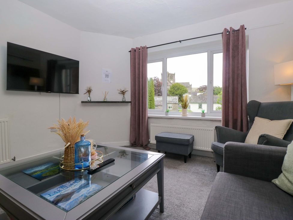 A living room with a television and coffee table at Courtyard Cottage in Cartmel