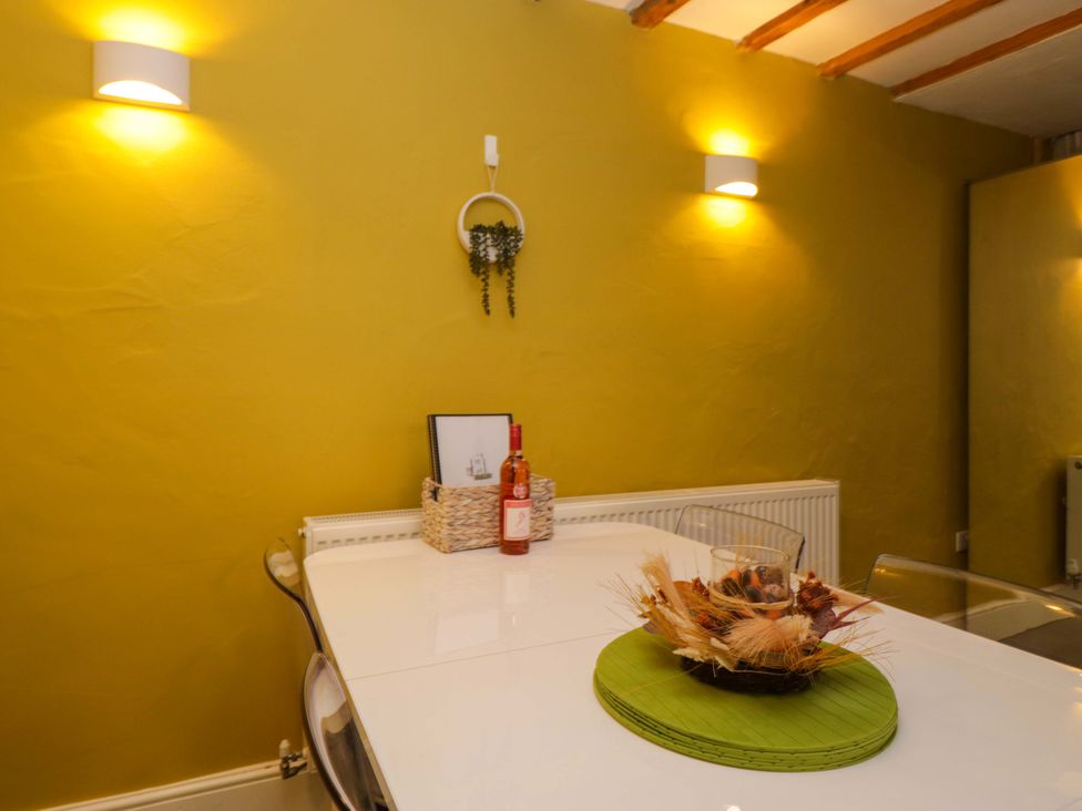 A dining room with a table and a wine bottle at Courtyard Cottage in Cartmel