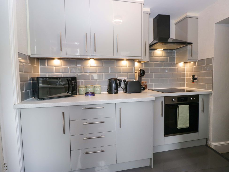 A kitchen with modern appliances at Courtyard Cottage cartmel