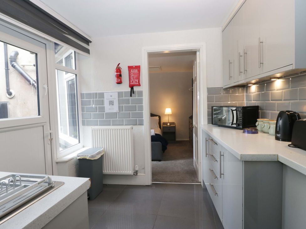 A kitchen with a microwave, kettle, and window at Courtyard Cottage in Cartmel
