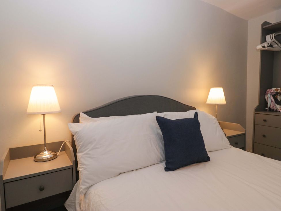 A bedroom with a bed and bedside lamps at Courtyard Cottage in Cartmel