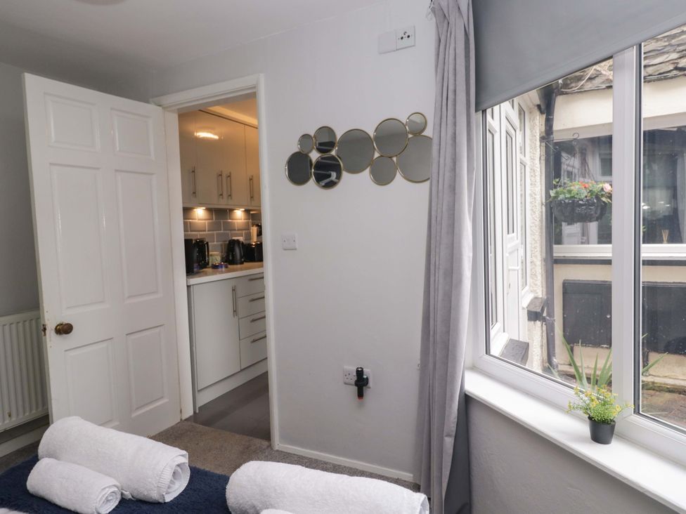 A bedroom with mirrors on the wall and a view of a kitchen at Courtyard Cottage Cartmel