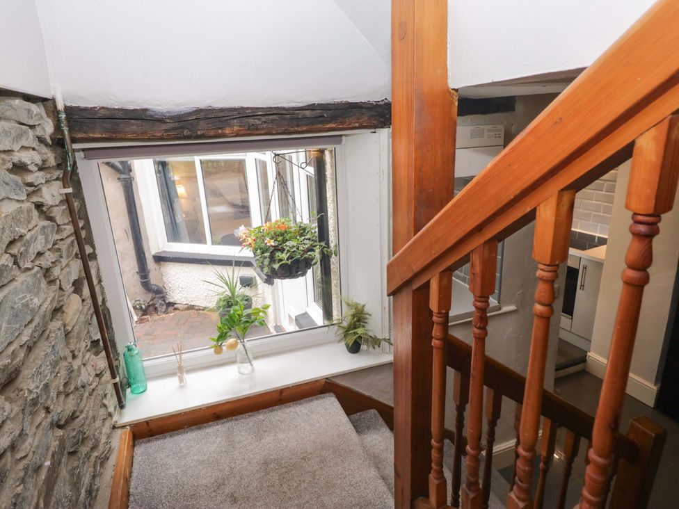 A staircase with a window and potted plant at Courtyard Cottage in Cartmel