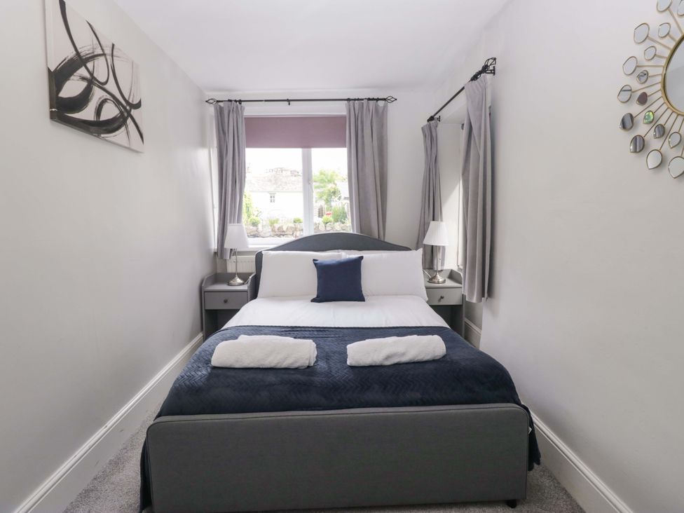 A bedroom with a bed and bedside tables at Courtyard Cottage Cartmel