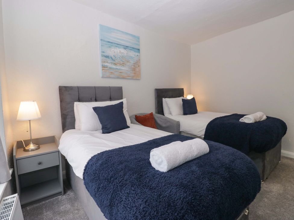 A bedroom with two beds and a painting at Courtyard Cottage, Cartmel