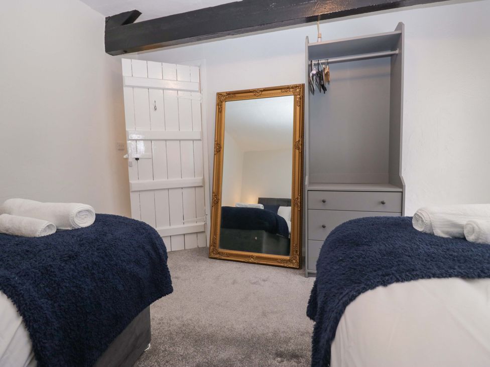 A bedroom with two beds and a mirror at Courtyard Cottage in Cartmel