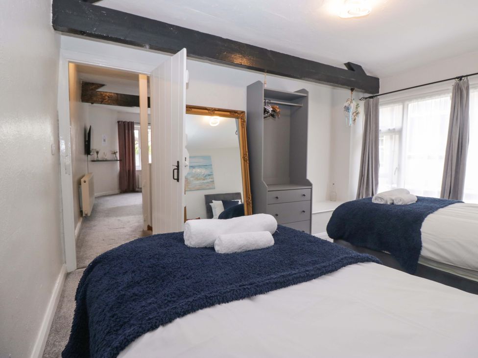 A bedroom with two beds and a mirror at Courtyard Cottage in Cartmel